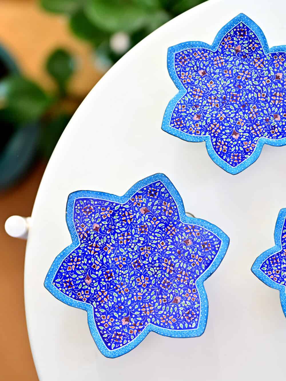 Enhance your home with this set of three Persian copper enamel (Minakari) star dishes, hand-painted with intricate floral designs in vibrant blue,