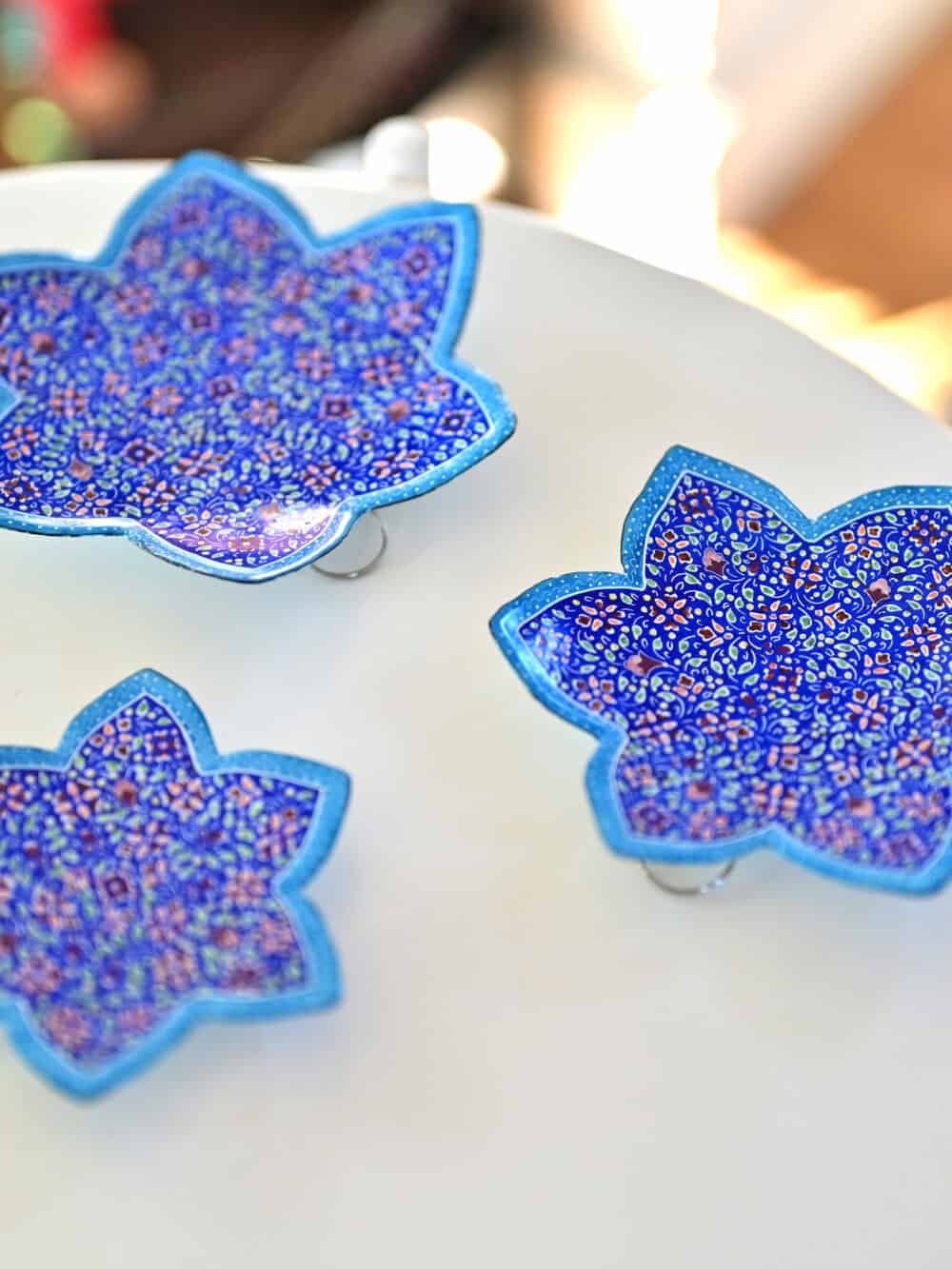 Enhance your home with this set of three Persian copper enamel (Minakari) star dishes, hand-painted with intricate floral designs in vibrant blue,