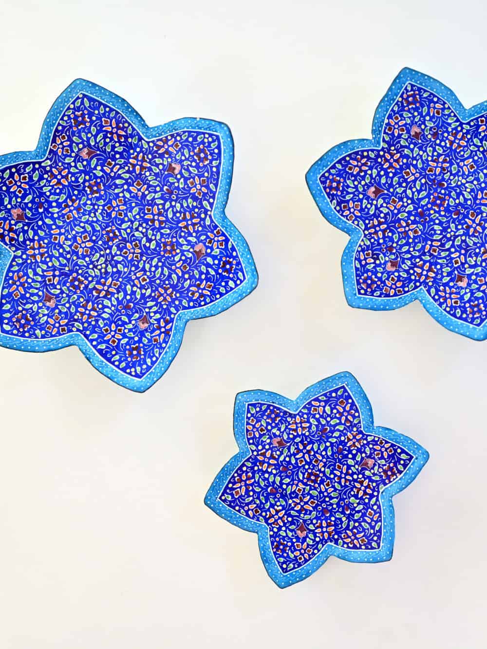 Enhance your home with this set of three Persian copper enamel (Minakari) star dishes, hand-painted with intricate floral designs in vibrant blue,